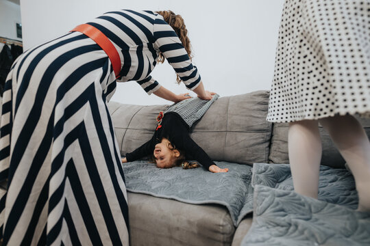 A child turns upside down while family members share fun moments in their home. Bright patterns, carefree activities, and familial warmth create an engaging household scene capturing childhood joy.