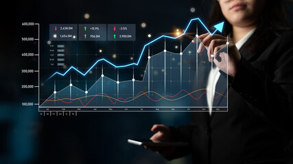 A professional businesswoman analyzes financial data through digital graphs in a modern office, focusing on trends and metrics for strategic insights and decision-making. Scalp