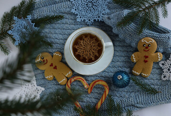 Christmas background: a tea mug with a decorative snowflake on a blue knitted item, top view