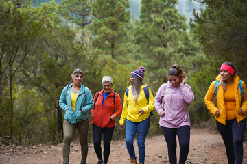 Group of happy multi generational women having fun during trekking day at mountain forest - Hiking, active lifestyle and multiracial people concept
