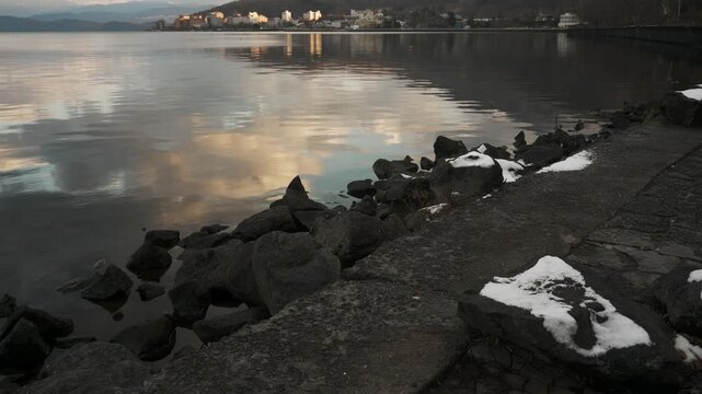 鏡面の水面とゴツゴツした岩のある晩秋の湖畔