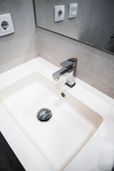 Fototapeta premium Modern bathroom sink with chrome faucet and mirror reflecting minimalist clean interior design details