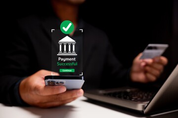 A person confirms a successful online payment using a smartphone while holding a credit card, with a computer in the background.