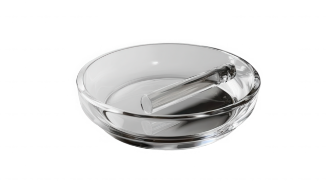 A clear glass bowl with a glass stirring rod resting inside against a black background in studio shot on transparent background