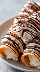 Delicious dessert showcasing ice cream-filled pastry rolls topped with whipped cream, chocolate drizzle, and chocolate shavings on a plate