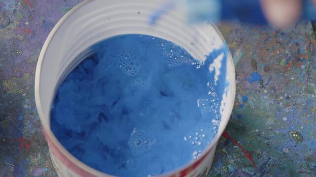 Blaue Farbe wird in einen Beh&auml;lter getr&auml;ufelt &ndash; k&uuml;nstlerische Studioaufnahme mit Fl&uuml;ssigfarbe, Tropfenbewegung und kreativem Mal- und Mischprozess