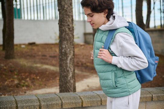 Teen Boy With Backpack Running Outdoors In Park During School Day