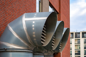 Metal ventilation ducts beside the brick building facade forming a distinctive technical infrastructure element within the housing estate
