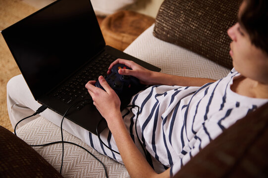Teen Gamer With Laptop And Controller On Couch - Casual Home Entertainment Scene