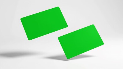 Two blank green cards floating and rotating in slow motion. Chroma key placeholders for credit cards, business cards, or gift cards