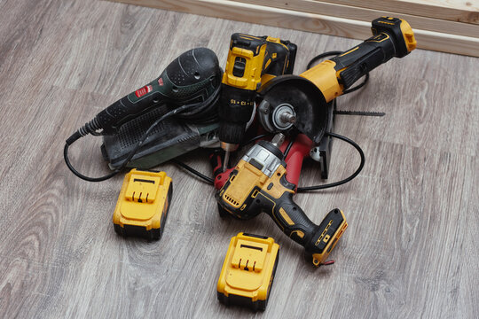 Cordless power tools and batteries on a wooden floor. Tools in an active workshop. Concept construction, home improvement and DIY craftsmanship.