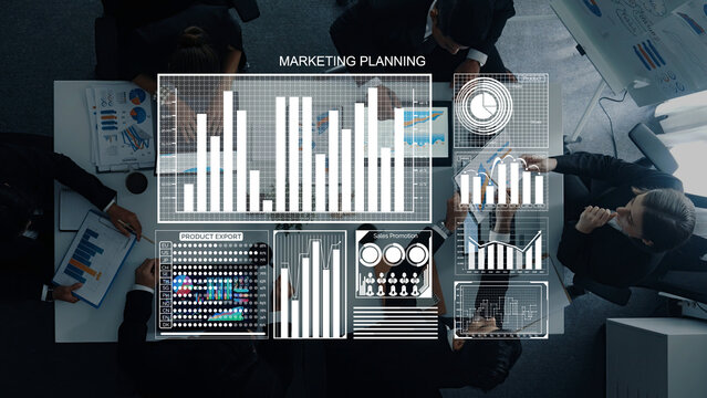 A diverse business team collaborates in a modern office, focused on marketing planning as they analyze digital charts and graphs for strategic insights. Axiom - Powered by Adobe
