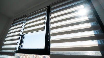 Zebra blinds illuminated by strong sunlight on high-rise apartment window with striped daylight pattern