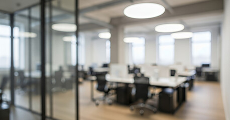 Bright office space filled with natural light creates a calm atmosphere, with blurred workstations and modern ceiling lights suggesting an open layout suited for collaborative tasks.