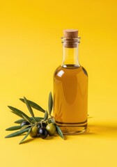 Glass bottle of golden olive oil with a cork stopper, next to a branch of green and black olives, isolated on a bright yellow background
