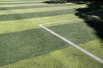 Patterned artificial turf surface with white field lines on a neighborhood sports ground under...