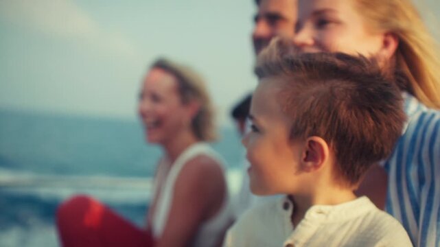 Cheerful family, including a young boy and adults, enjoy a peaceful boat trip on the ocean. They are smiling and watching the horizon, experiencing joyful moments together on vacation.