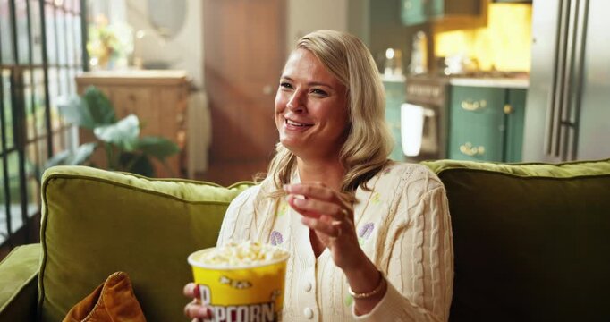 Woman, watching tv and laugh with popcorn on sofa for funny movie, streaming and relax in home. Person, happy and eating snack with film subscription, comedy or television in lounge at apartment