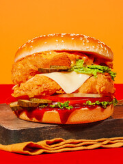 Juicy Crispy Chicken Burger with Cheese, Pickles, and Sauce on Wooden Board