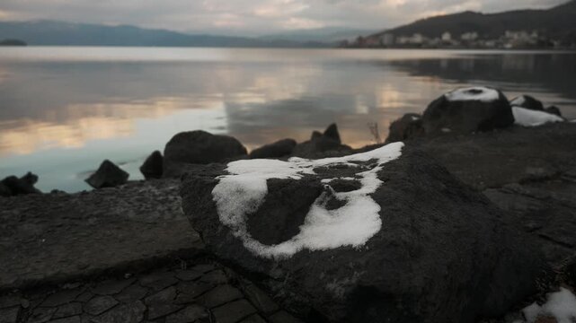 鏡面の水面とゴツゴツした岩のある晩秋の湖畔