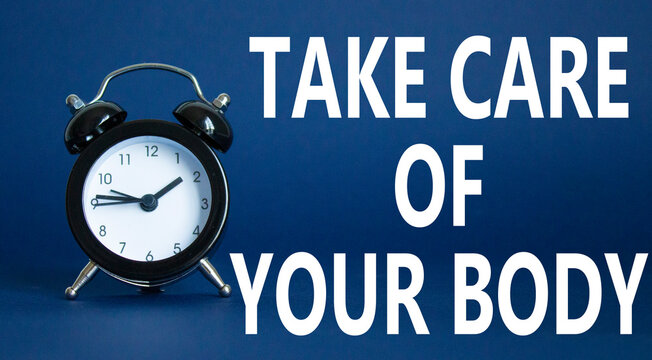 Health symbol. Wooden blocks with words Take Care of your Body. Beautiful deep blue background with alarm clock. Health concept. Copy space.