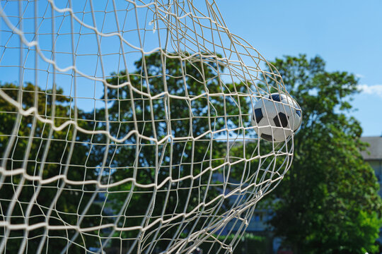 Soccer ball in soccer goal net in a big stadium isolated on blue sky. soccer net.