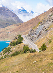 Scenic view of French alps in Savoie region call Col du Mont-Cenis surrounded with mountain, rocky road and village with cloudy drama sky, an altitude  in the municipality of Val-Cenis in France.