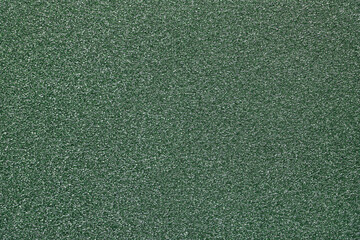 Green glitter textured paper showing gleaming particles, suitable for festive, celebration, or...