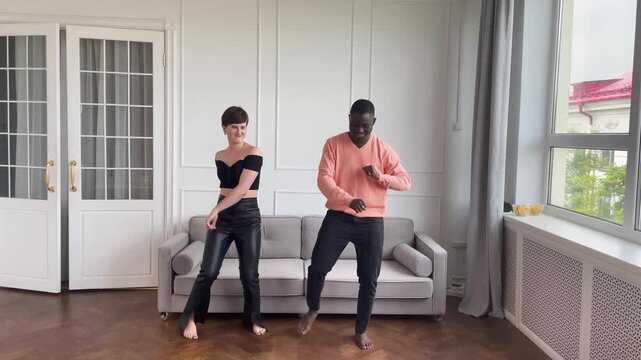Couple of young african american man and caucasian woman dancing at home