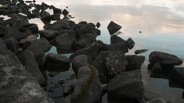 鏡面の水面とゴツゴツした岩のある晩秋の湖畔