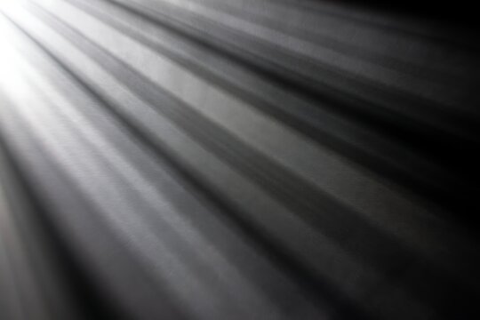 Diagonal light rays shining across a dark textured surface.