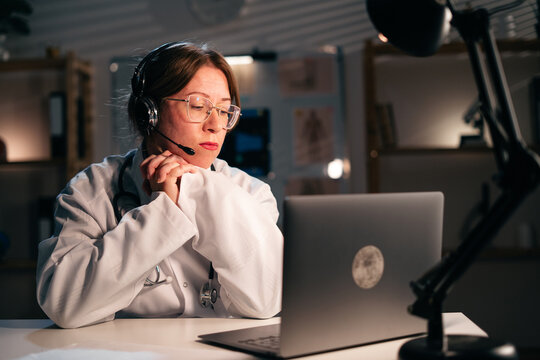 Doctor Using Headset Consulting Patient Telemedicine Hotline Night Shift Hospital