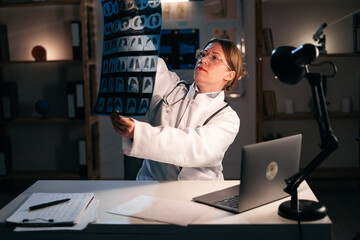 Doctor woman looking at x ray scan working late at night. Physician analysis and examination patients result. Professional Medic