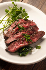 Fine dining plate of medium-rare steak with microgreens on a white plate. 