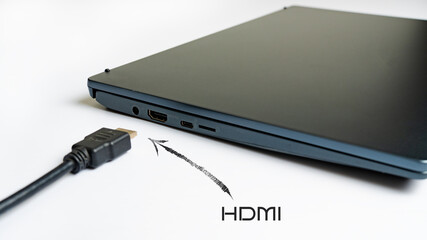 Is connecting black HDMI cable into HDMI port of the modern laptop on white background. Arrow pointer with the label HDMI