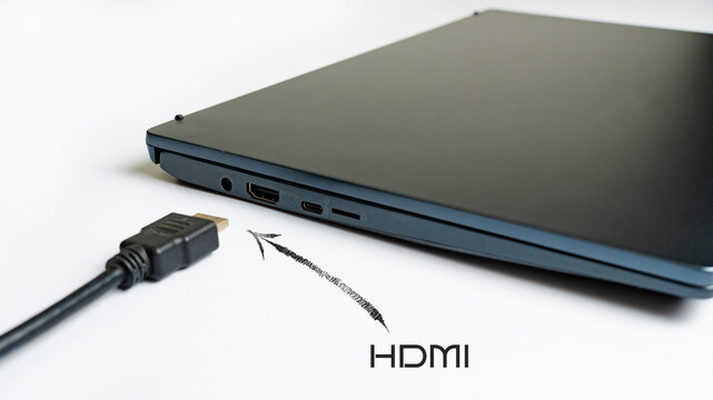 Is connecting black HDMI cable into HDMI port of the modern laptop on white background. Arrow pointer with the label HDMI