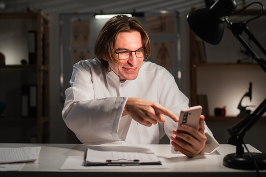 Male Doctor in White Coat Reading Social Media using Phone in Hospital during Night Shift - Powered by Adobe