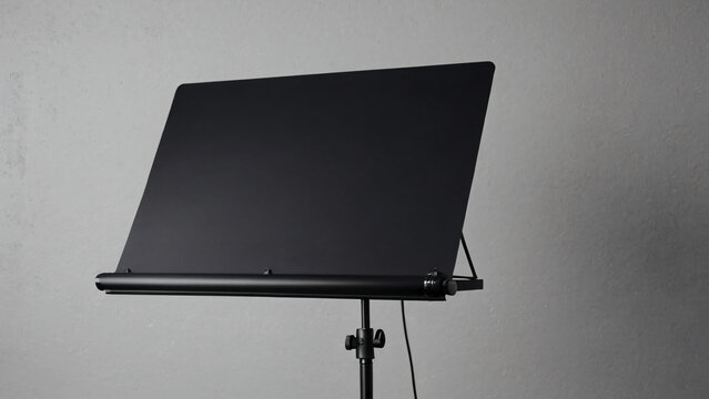 Nahaufnahme eines modernen schwarzen Notenpults vor grauem Hintergrund