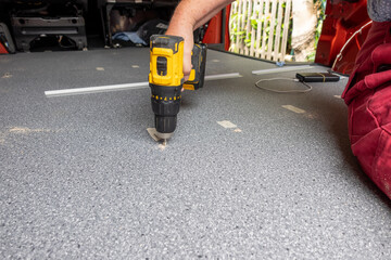 Frau verschraubt eine Bodenplatte im Wohnmobil Camper van conversion