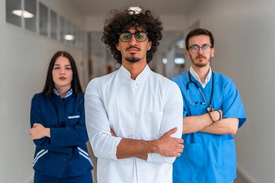 A diverse medical team consisting of doctors and a nurse stand in a hospital corridor with arms crossed. The portrait showcases healthcare professionals highlighting their expertise to medicine. - Powered by Adobe