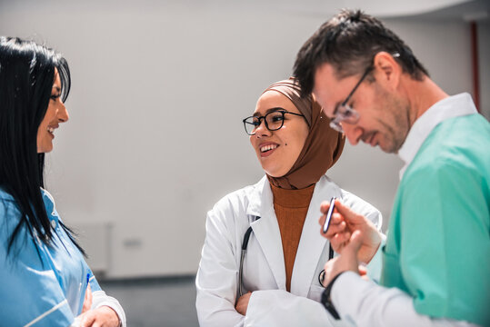 A diverse medical team collaborates discussing patient care in a hospital. The healthcare professionals dressed in uniforms share their expertise and insights to provide the best possible treatment.