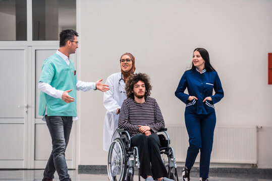 Diverse Medical Staff With Patient In Wheelchair Walking Down Hospital Hallway Healthcare Professionals Providing Assistance And Support