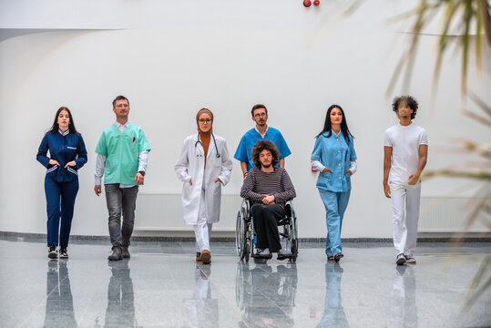 Diverse medical team consisting of a doctor nurses and a patient in a wheelchair walking together in a hospital hallway. This image is suitable for healthcare medicine and medical concepts.