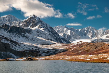 Close up photo of Altai mountain lake and snow capped ridge against blue sky