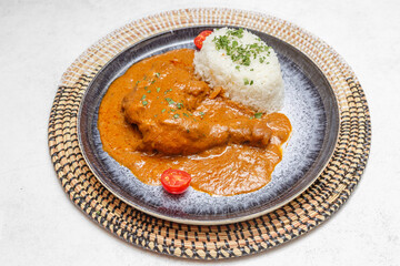 Mafé poulet sur assiette bleue avec set tissé africain. Cuisine africaine traditionnelle. Traiteur africain.
