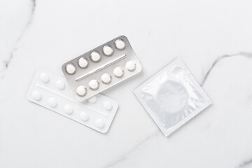 Contraceptive pills and condoms on marble background, top view. birth control methods