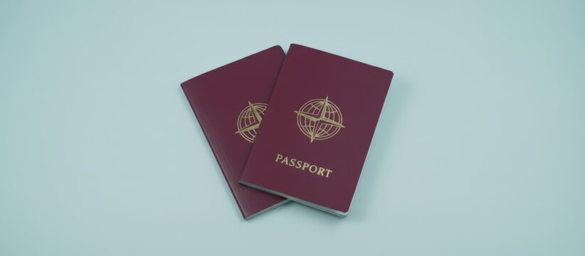Two identical burgundy passports with a golden globe emblem and passport text are resting together on a simple light blue surface, representing travel, identity, and international citizenship