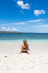 Woman sitting on white sand beach enjoying tropical ocean view