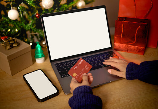 Holiday online shopping on laptop with credit card and smartphone supporting secure digital payments festive e-commerce purchases seamless checkout processes seasonal consumer behavior