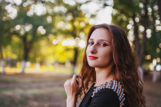 Elegant woman outdoors with soft evening light and natural bokeh background